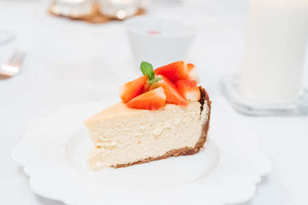 Fresh strawberry cheesecake on a ceramic plate on a white tableの写真素材