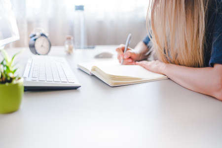 Woman leaning on office desk, working with a laptop at homeの写真素材
