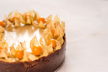 freshly baked, whole New York cheesecake garnished with physalisの写真素材