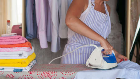 Happy young beautiful woman ironing clothes. Houseworkの写真素材