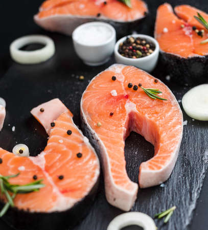 Raw salmon fish steaks with fresh herbs on cutting boardの写真素材