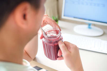man working on the computer and drinking smoothie in home officeの写真素材