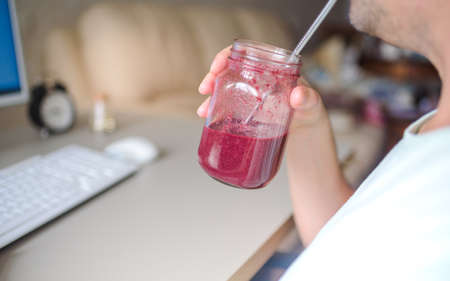 Freelancer working on the computer and drinking smoothie in creative officeの写真素材