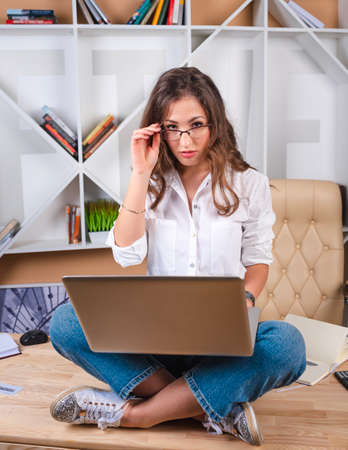 Girl student studying foreign languages online, sitting in lotus position with a laptopの写真素材