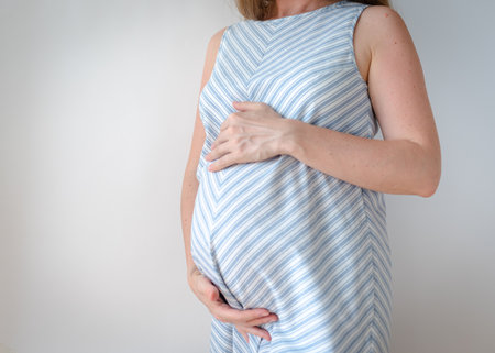 pregnant woman standing holding her hands on her stomachの素材 [FY310187426844]