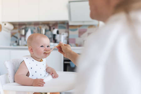 babys first feeding, mom feeds a baby with a spoonの写真素材