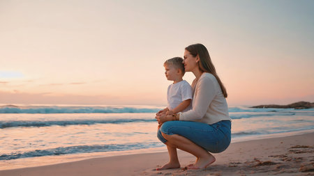 Mother and son sitting on the beach at the sunset. Concept of friendly family.の素材