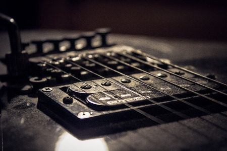 guitar bridge and strings close up with dusty coils and magnetsの写真素材