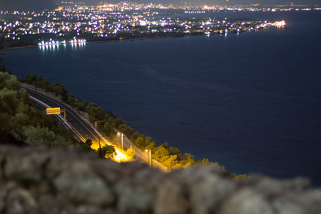 nightscape scenery of a highway ocean and a town on the horizonの写真素材