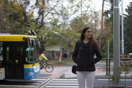 girl standing and thinking a bus and a bike pass behind her at a pavementの写真素材