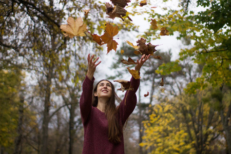 girl at a park thowing leaves in the air autumn scenery yellow leaf fall adult pretty