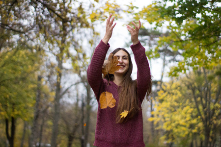 girl at a park thowing leaves in the air autumn scenery yellow leaf fall adult prettyの写真素材