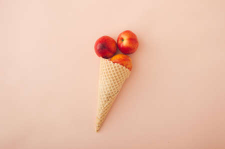 Ice cream waffle cone with peaches inside on pink background. Minimal summer concept.の写真素材