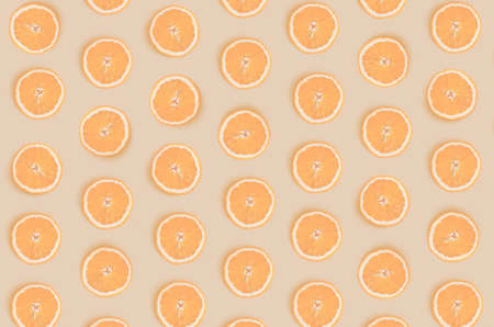 Fruit pattern from round orange slices isolated on light orange background. View from above.の写真素材