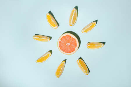 Orange slices arranged around a red grapefruit on a blue background.の写真素材
