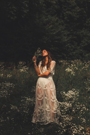Beautiful portrait of a woman in a white dress in the middle of a flower fieldの写真素材
