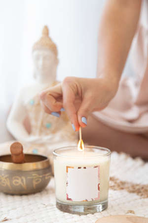 meditation space with candles and woman in lighting up a candle in the backgroundの写真素材