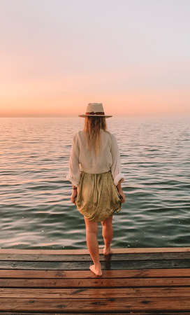 woman staring at a sunset by the lakeの写真素材