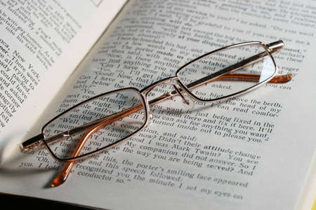 Glasses laying on page of the open bookの写真素材