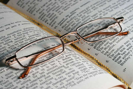 Glasses laying on page of the open bookの写真素材