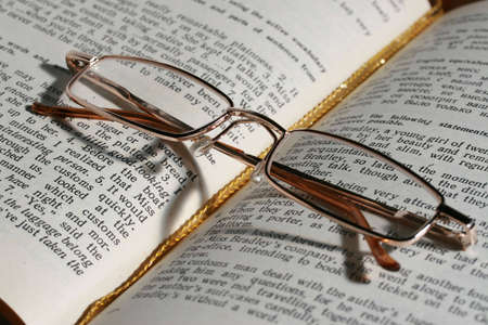 Glasses laying on page of the open bookの写真素材