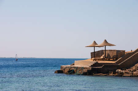 Surfing and beach with umbrellas and chaise loungesの写真素材