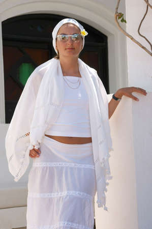 The girl in a white dress and a scarf standing on a verandahの写真素材