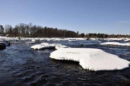 A river in Sweden surrounded by snow in springの写真素材