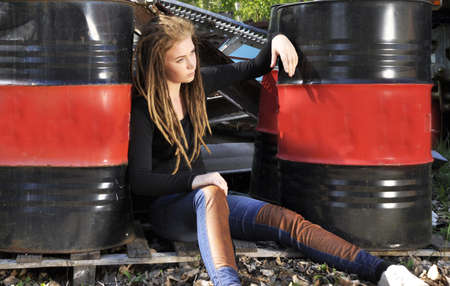 A young fashion model posing surrounded by oil drumsの写真素材