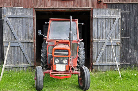 An antique tractor parked in front of an old barnの写真素材