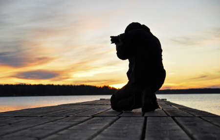 Silhouett of a photographer in a lake at sunriseの写真素材