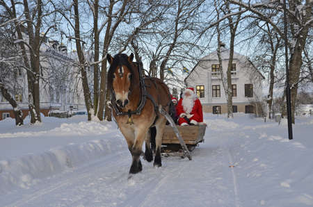 Gysinge, Sweden - December 08: Santa claus goes to sleigh with brown horse at Christmas time in Gysinge on December 08, 2012 in Gysinge Sweden.のeditorial素材