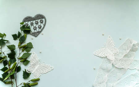 Flatlay mockup composition with copyspace, lace, textile butterflies in vintage style, pearls, young birch tree branches, laced vintage heart on the light green background, concept to display your artの写真素材