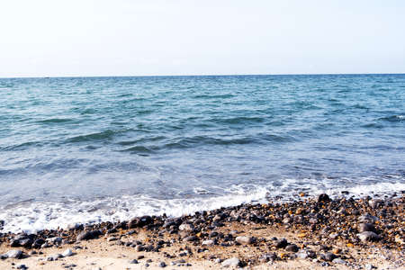 Tender ocean waves and pebbles on the coast line, blue sea waters on a sunny day, beautiful seascape natural backgroundの写真素材