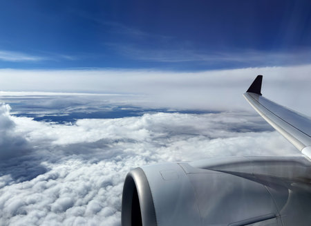 Aerial view of sky and clouds from above seen through the aircraft window, travelling by plane,...