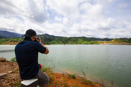 Man is sitting to take a photo of landscape の写真素材