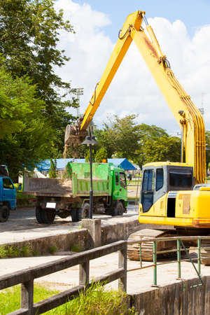 Excavator machine loading soil or sand into truck body