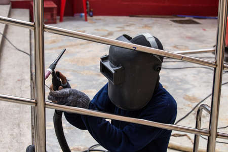 Welder working a welding metal with protective mask and sparks.