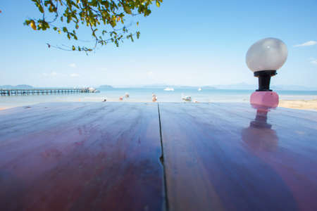 Wood table top on blurred blue sea and white sand beach backgroundの写真素材