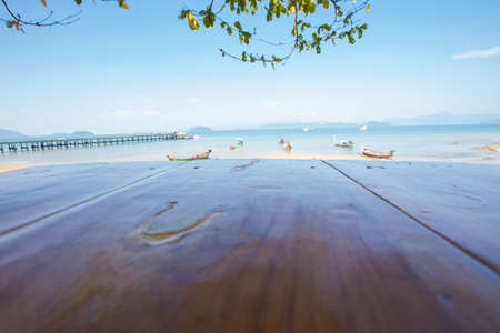 Wood table top on blurred blue sea and white sand beach backgroundの写真素材