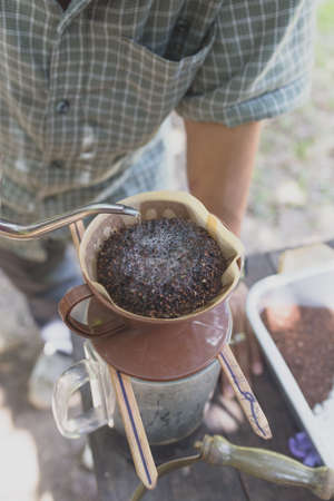 vintage Barista pouring water on coffee ground with filter outdoor.の写真素材