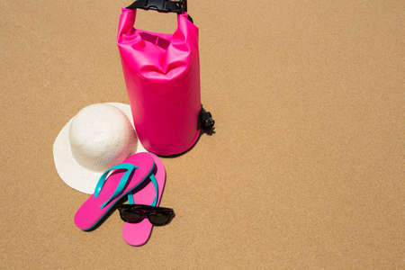 sunglasses, Waterproof bag, straw hat and flip flops on tropical beach.の写真素材