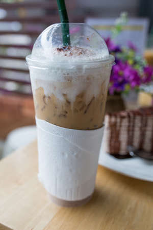 coffee plastic cup and cake on wood table.
