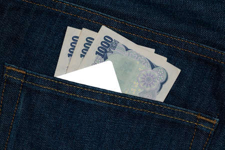 Card and  Japanese yen currency bank note in a back pocket of a denim jean.