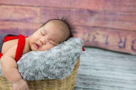 Cute baby boy sleeping in a basket.の写真素材