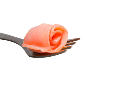 Roll of salmon slice on a fork, isolated on whiteの写真素材