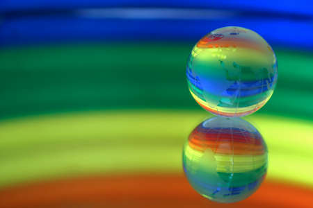 Globe on a surface of a mirror. On a multi-coloured background.の写真素材