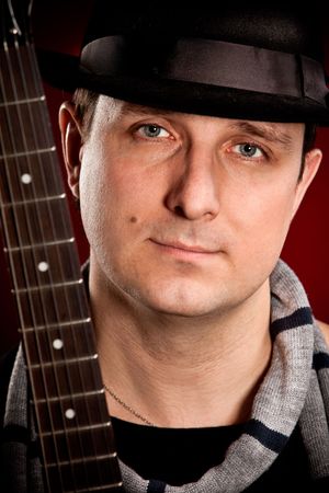 man with a guitar on a dark red background