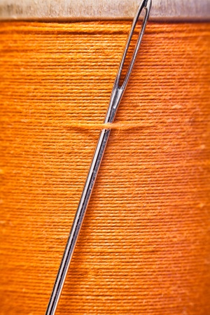 Spool of yellow thread with a needle stuck in it.の写真素材