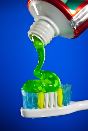 toothpaste being squeezed onto a toothbrush on a dark blue background